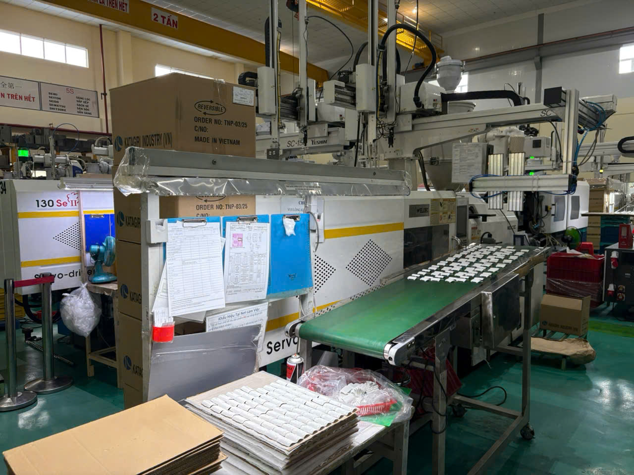 Injection molding machine on factory floor in Vietnam producing plastic parts