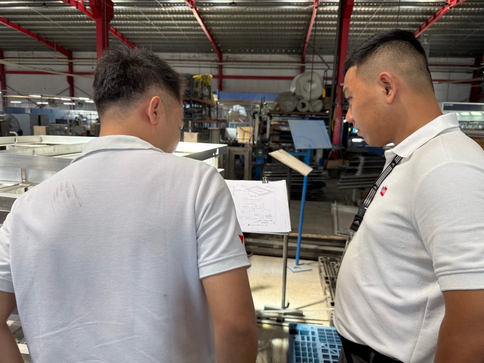 DEWIN engineers reviewing frame drawings on the factory floor
